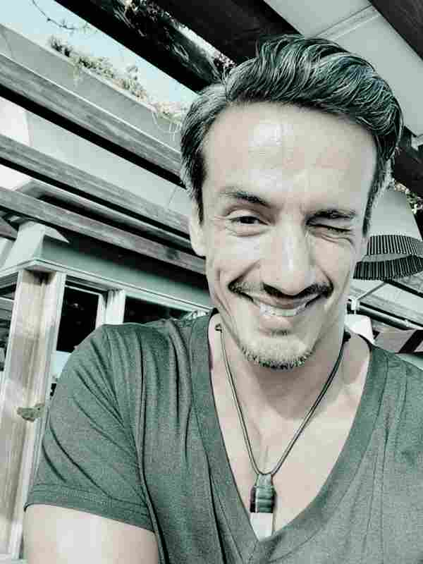 Escort Mann Cesar von haut-nah.org lächelt mit Augenzwinkern
