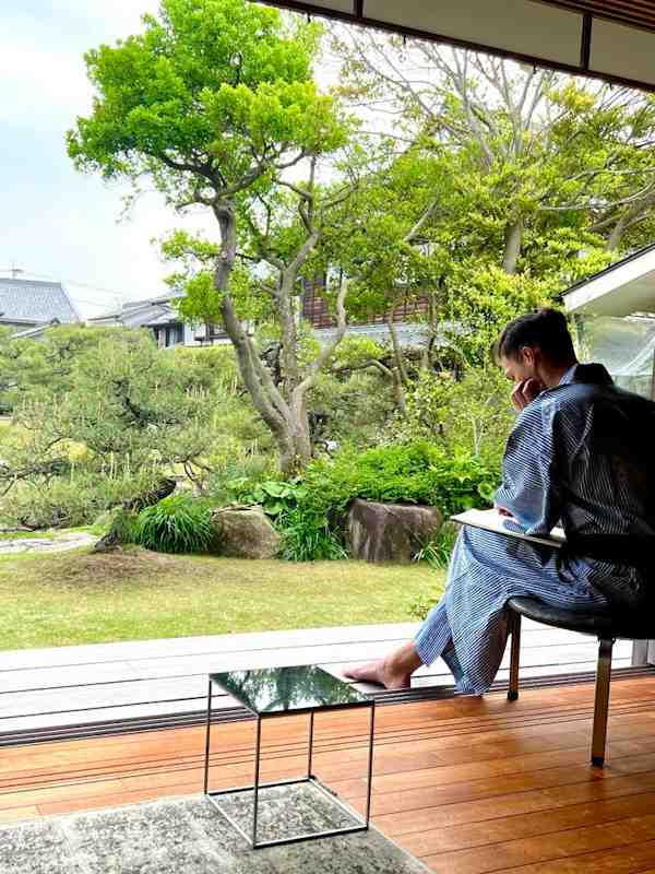 Callboy Noah von haut-nah.org sitzt gedankenversunken vor exotischen Garten