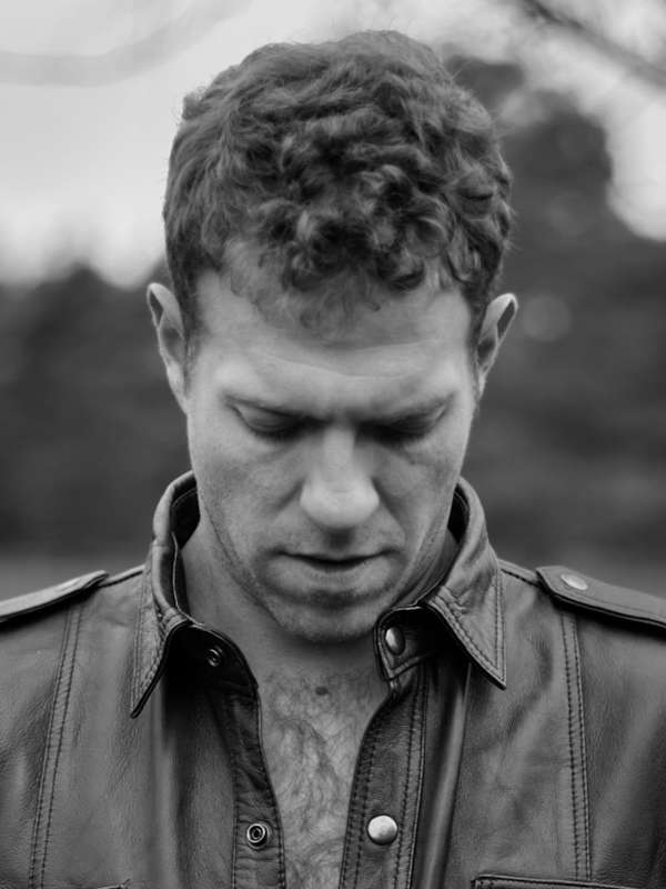 Callboy Simon von haut-nah.org schaut nach unten, in Lederjacke