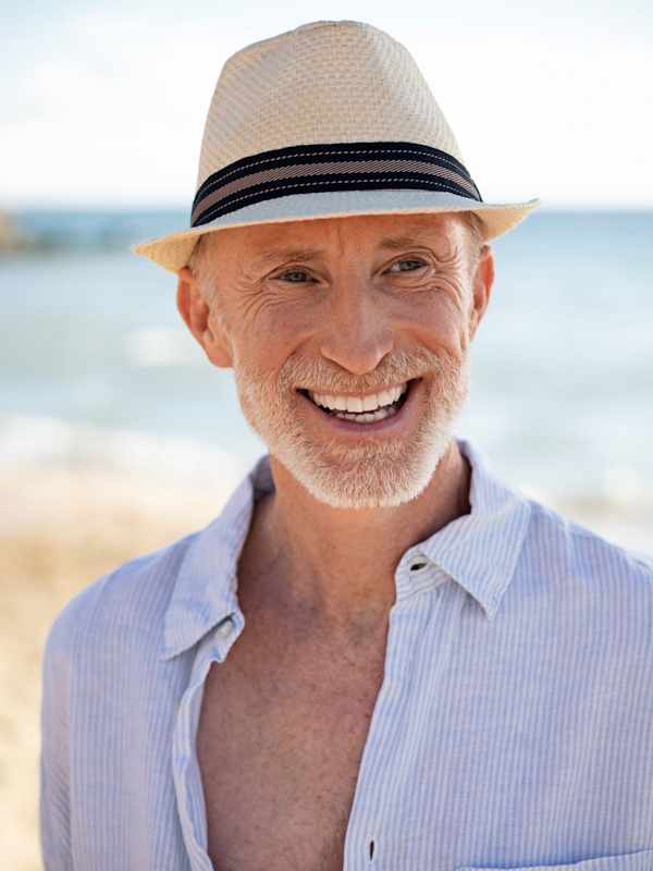 Escort Mann Robert von haut-nah.org mit Hut und im Freizeitlook, lächelt zur Seite