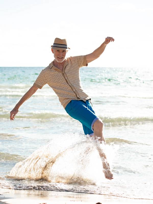 Escort Mann Robert von haut-nah.org mit Hut, springt über eine Meereswelle