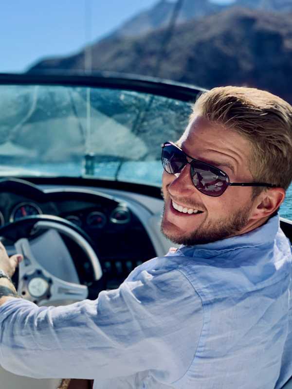 Callboy Maximilian von haut-nah.org mit Sonnenbrille fährt Boot