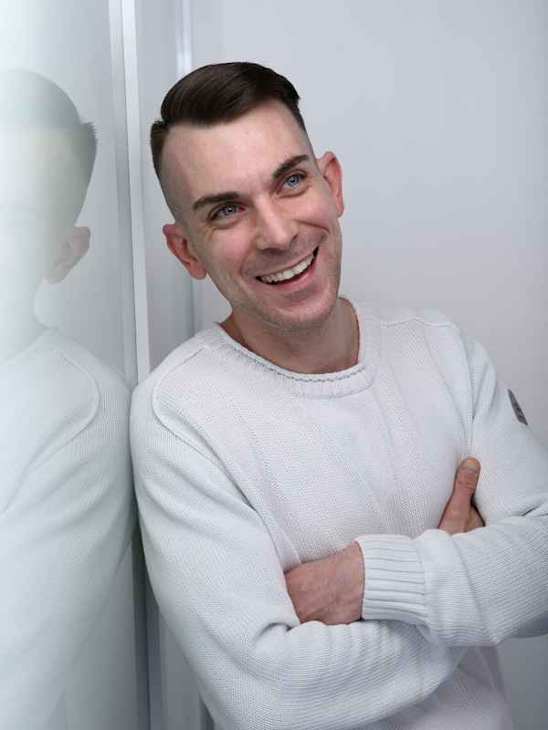 Callboy Dennis von haut-nah.org im weißen Pullover lächelnd mit Blick nach oben