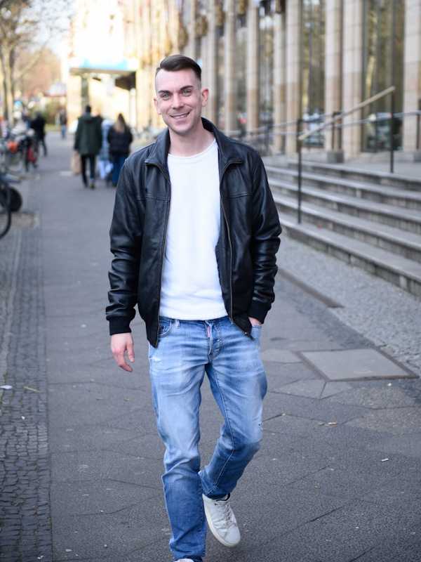 Escort Mann Dennis von haut-nah.org in Lederjacke und Jeans läuft durch die Stadt