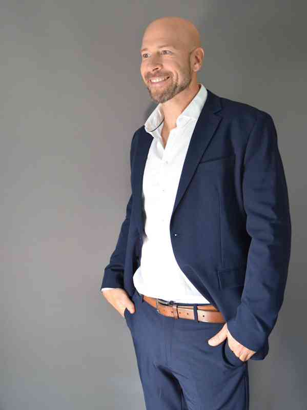 Escort Mann Stefan von haut-nah.org im blauen Anzug stehend mit seitlichen Blick