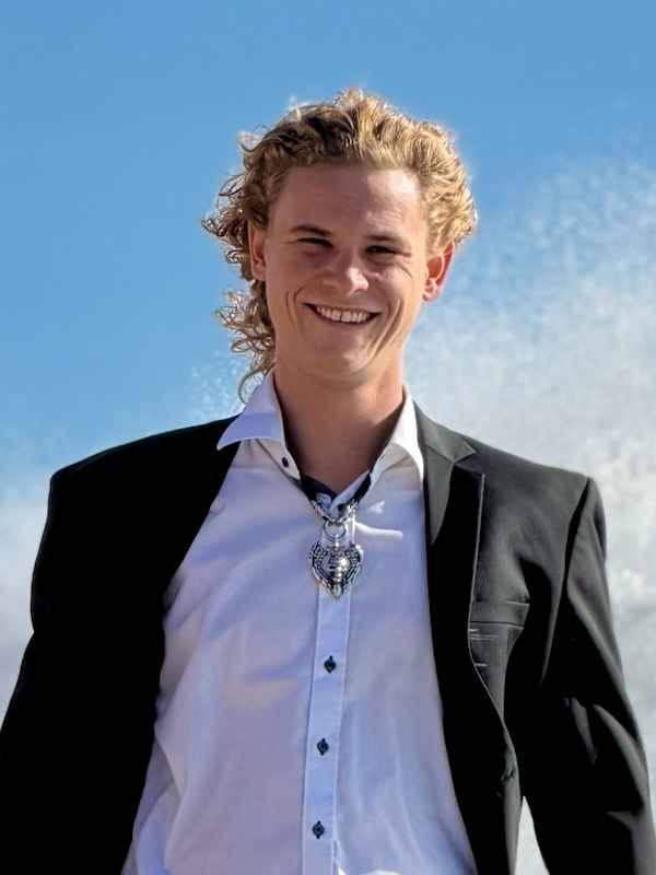 Callboy Xavier von haut-nah.org in Jeans, weissen Hemd und schwarzen Jacket auf Felsen vor dem Meer