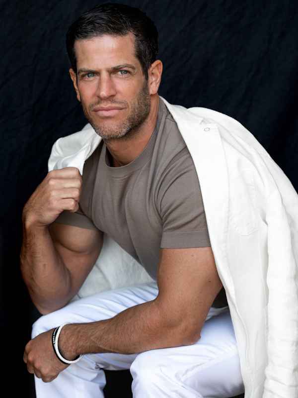 Escort Mann Chris von haut-nah.org lässig mit Jacket über dem Rücken und grauen Shirt