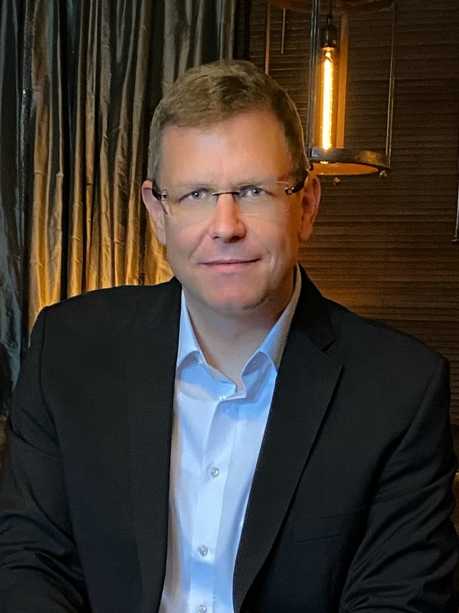 Callboy Alexander von haut-nah.org im Anzug auf Ledersessel lächelt leicht