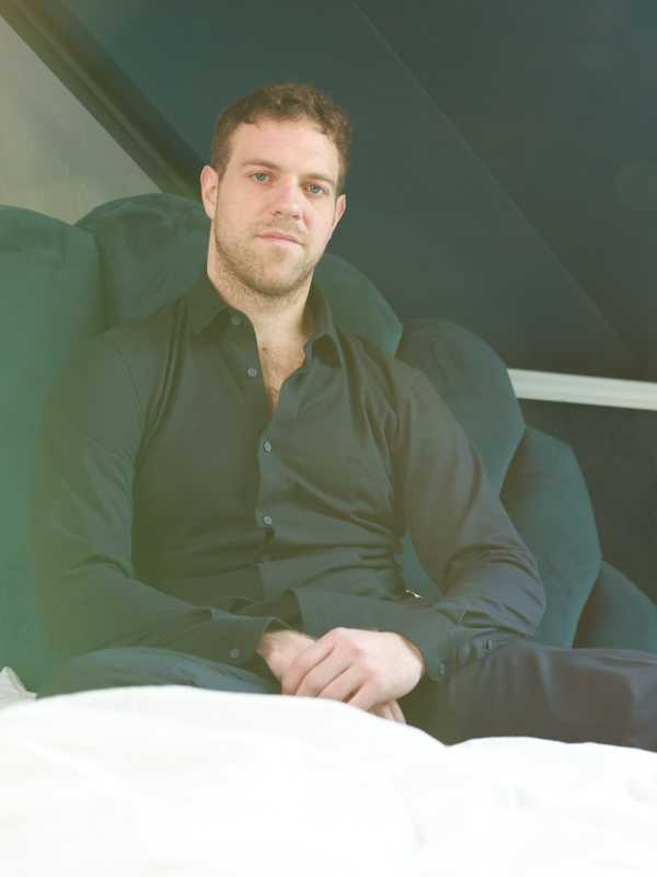 Callboy Simon von haut-nah.org im blauen Dress sitzt auf Bett