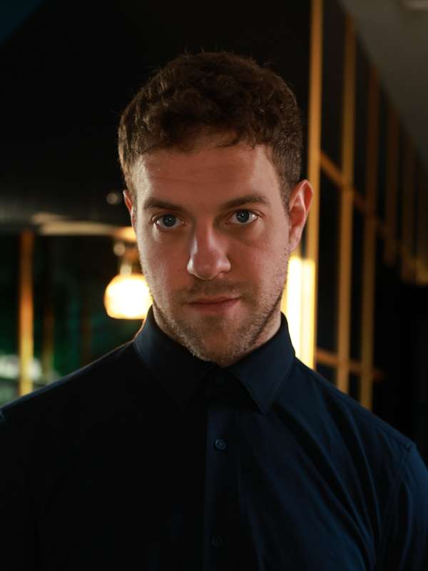 Escort Mann Simon von haut-nah.org knöpft Ärmel vom blauem Hemd zu