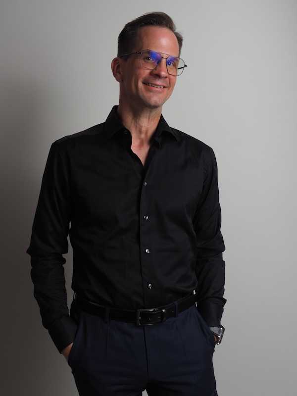 Escort Mann Thomas von haut-nah.org im schwarzen Hemd, Hände in den Taschen