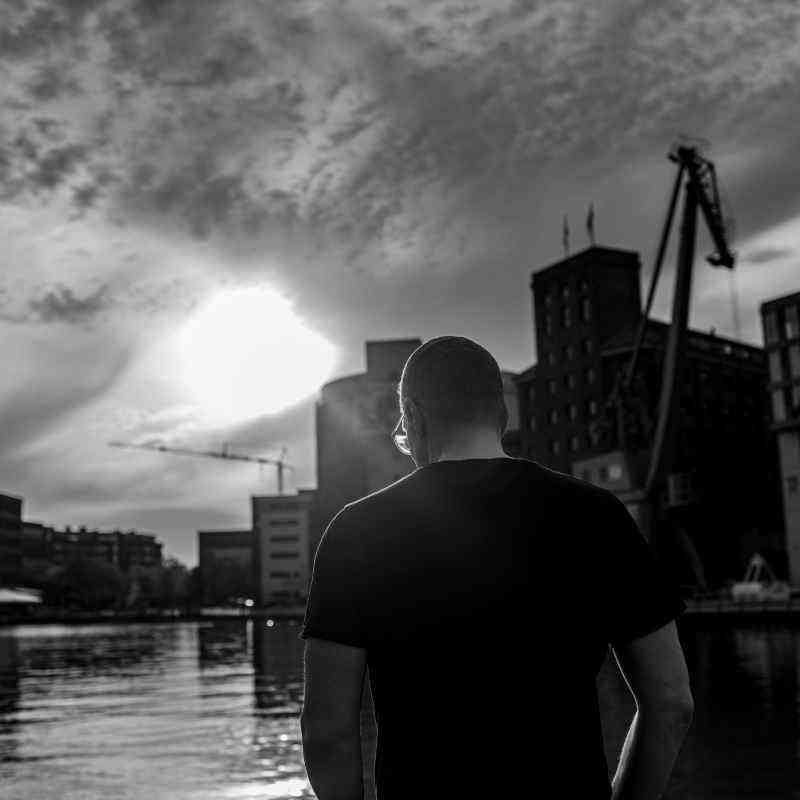 Callboy Alexander von haut-nah.org Rückenansicht vor Fluss, aufgerissene Wolken