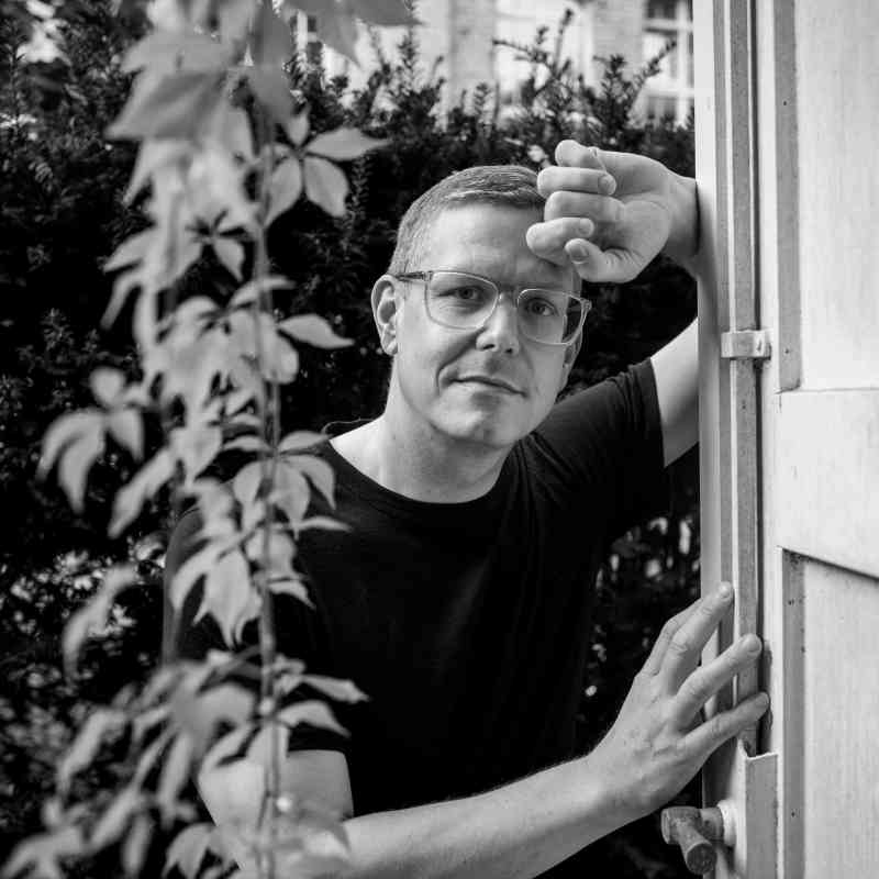 Escort Mann Alexander von haut-nah.org im Garten angelehnt vor Pflanzengewächs