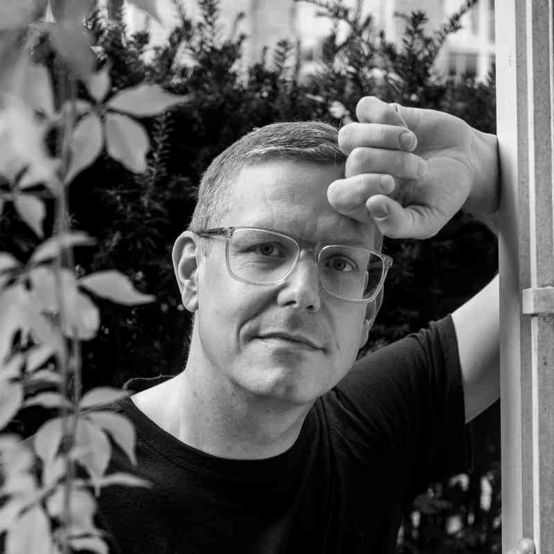 Escort Mann Alexander von haut-nah.org im Garten angelehnt vor Pflanzengewächs