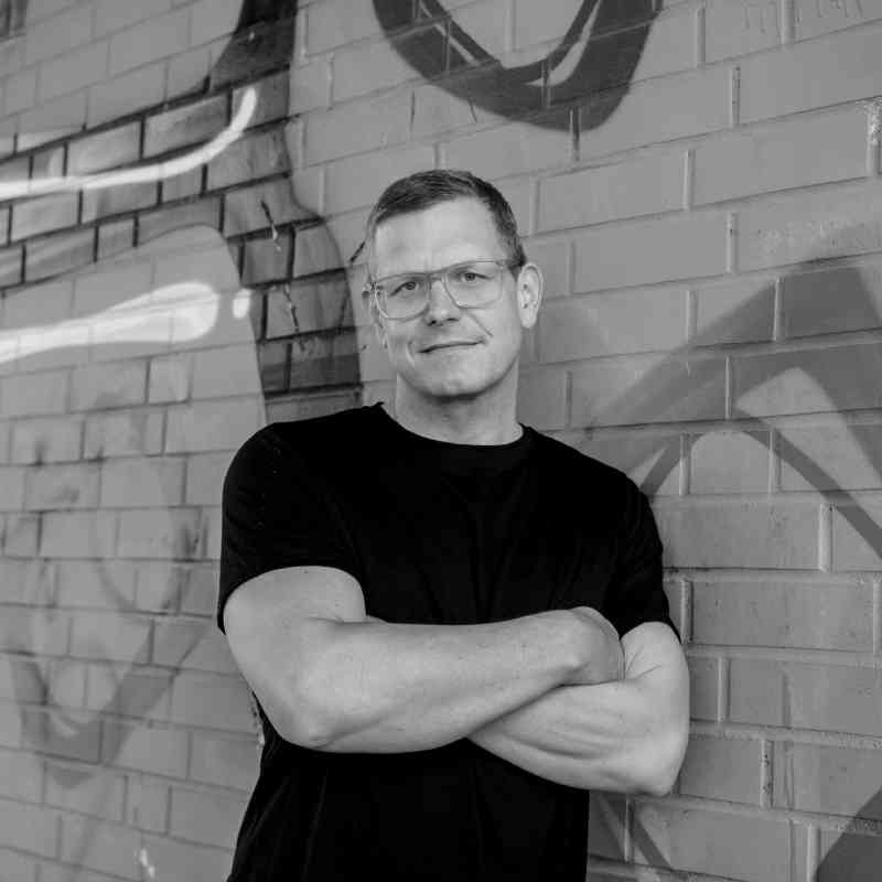 Escort Mann Alexander von haut-nah.org angelehnt an Graffitiwand, Arme verschränkt