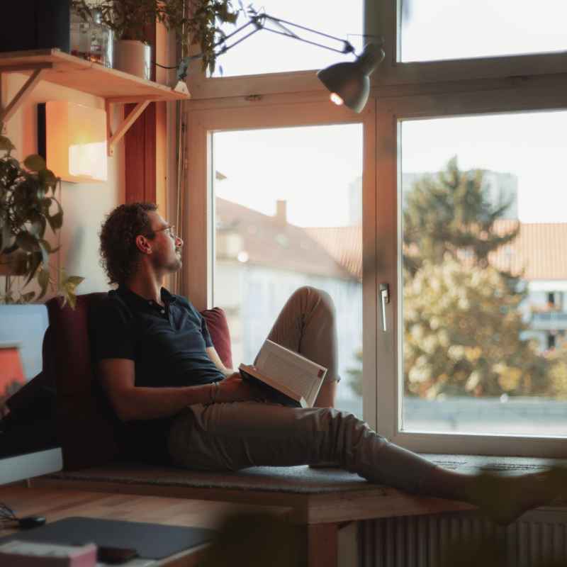 Escort Mann Malte von haut-nah.org mit Buch in der Hand, liegend am Fenster